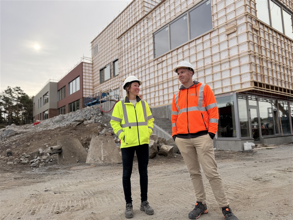 To mennesker foran en skole som er under bygging. - Klikk for stort bilde