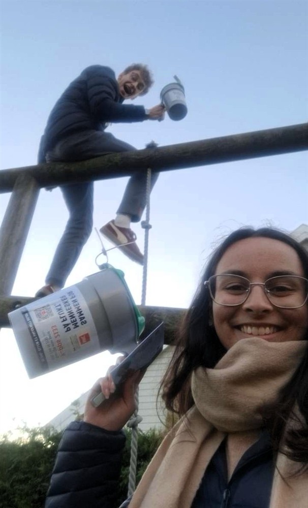 To unge mennesker med bøsser. En av dem sitter oppe i noe som likner på et lekestativ - Klikk for stort bilde