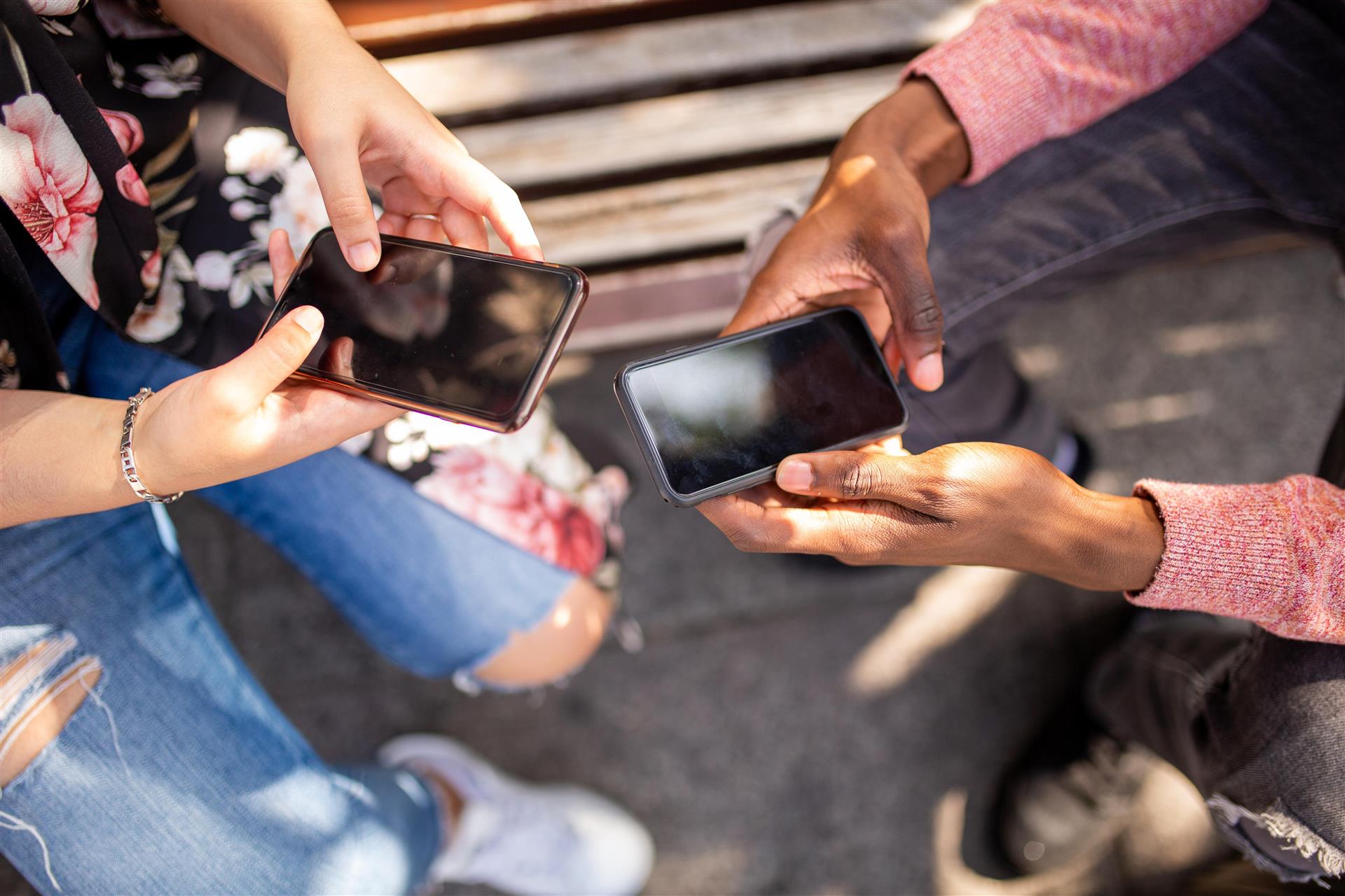 Hendene til to personer som holder hver sin mobiltelefon
