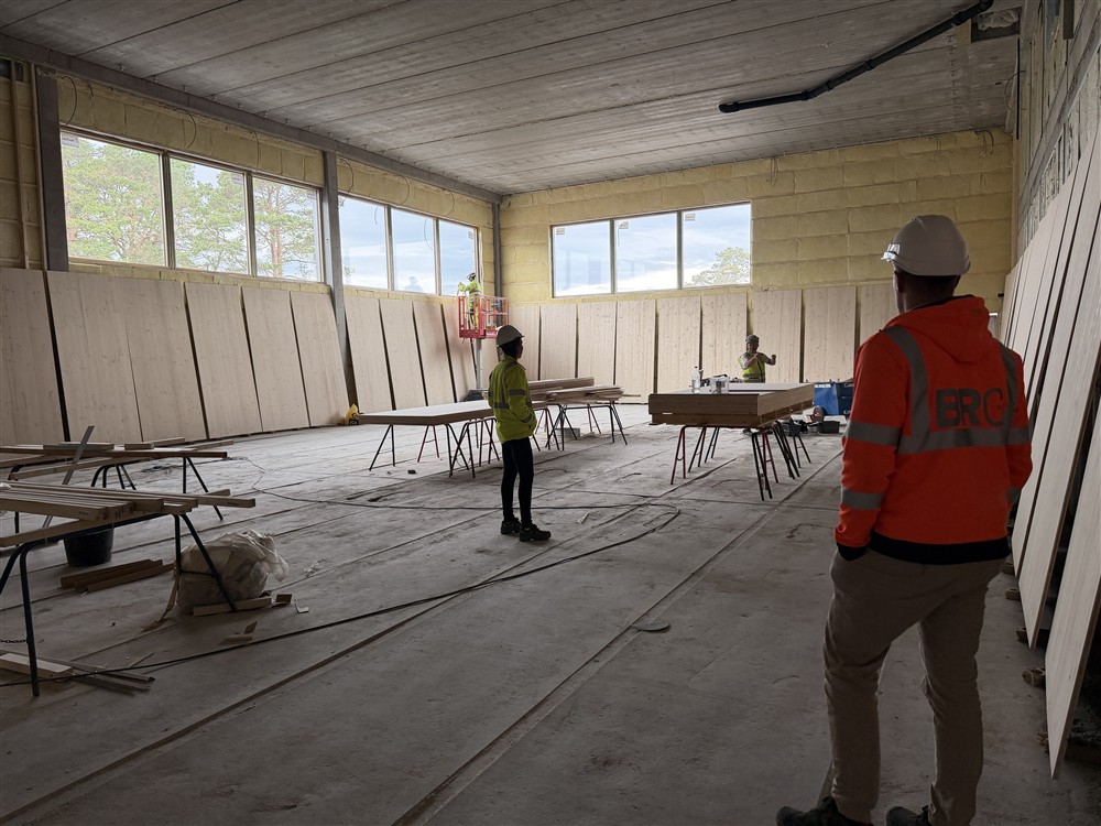 Et stort rom under oppføring, mennesker jobber og mennesker ser rundt seg. - Klikk for stort bilde