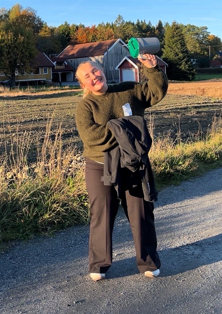 Ung dame med en bøsse. Et jorde bak henne - Klikk for stort bilde