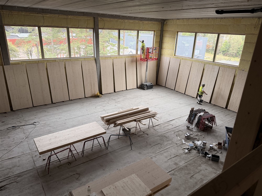Stort rom sett ovenfra. Materiell på gulvet, arbeidere jobber med veggene og vinduene som er høyt oppe i rommet.  - Klikk for stort bilde