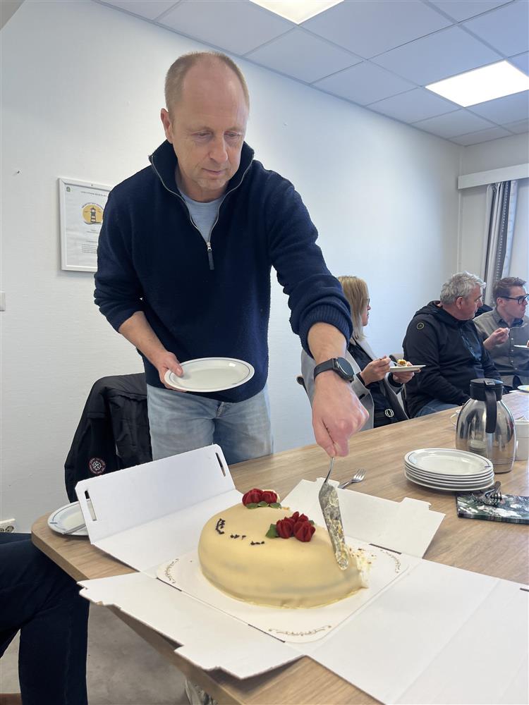Arve Falk Lorentzen forsyner seg av en bløtkake som står på et bord. Bak han sitter folk og spiser.  - Klikk for stort bilde