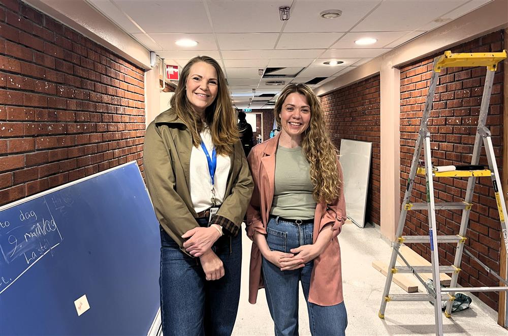 Ida K. S. Heiskel og Maria Odberg står i en gang som holder på å bli pusset opp. En stige står på gulvet - Klikk for stort bilde
