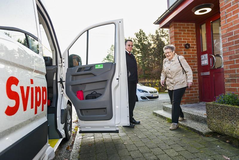 En mann holder døren åpen til en taxi, en eldre dame er på vei til å gå inn