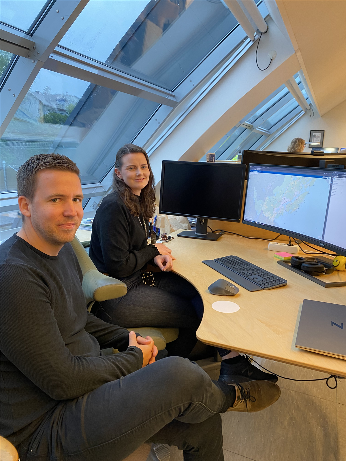Simon Ludvigsen og Mette Katla Austad sitter ved siden av hverandre på arbeidsplassen til Mette.  - Klikk for stort bilde