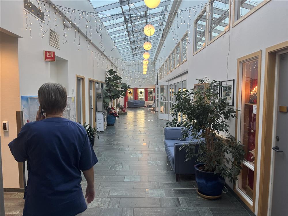 Gang som er pyntet med julelys, julepynt og menneske som prater i telefon - Klikk for stort bilde