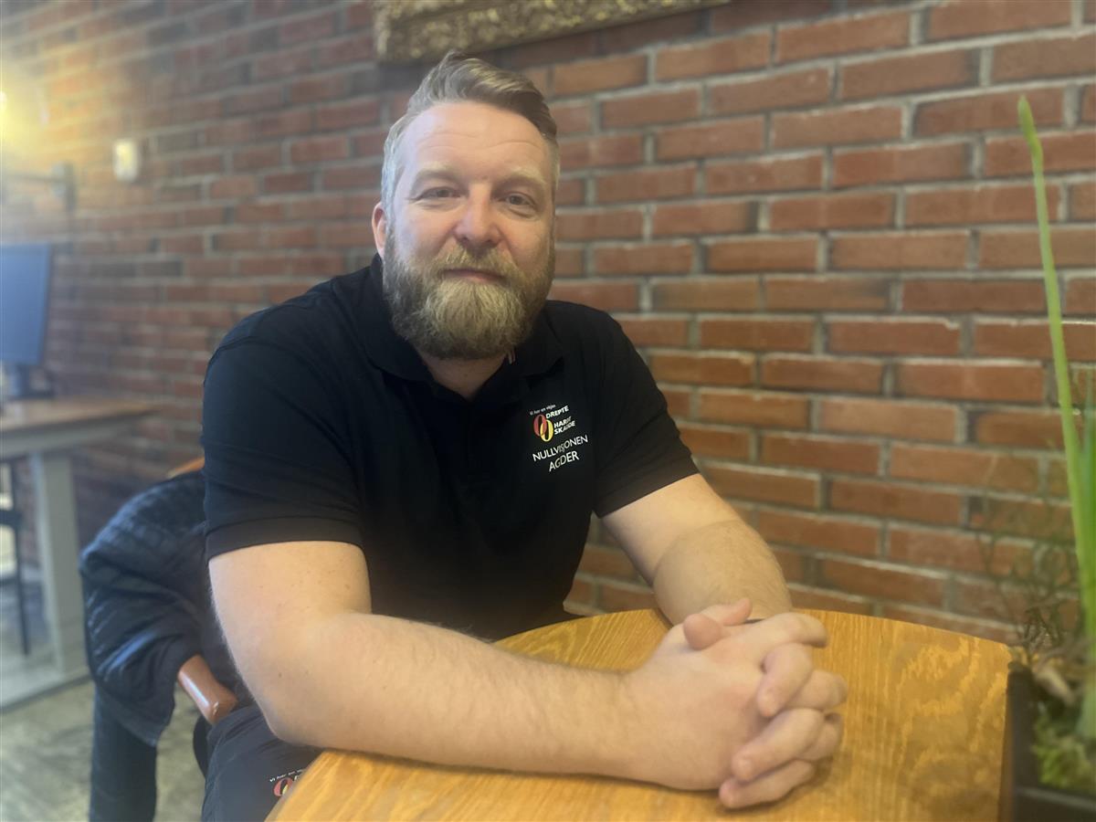 Svein Ture Gundersen sitter ved et bord og smiler - Klikk for stort bilde