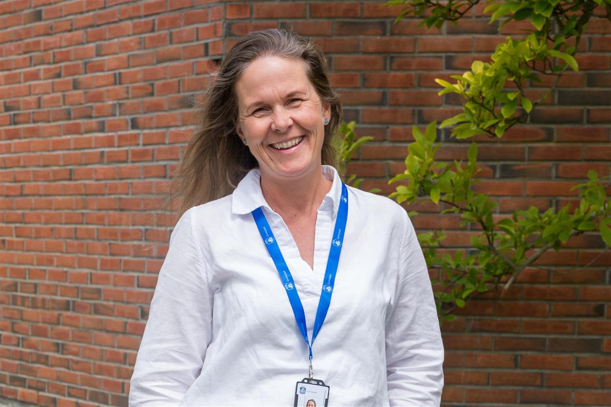 Ingunn Meyer Norschau står ute foran en mursteinsbygning - Klikk for stort bilde